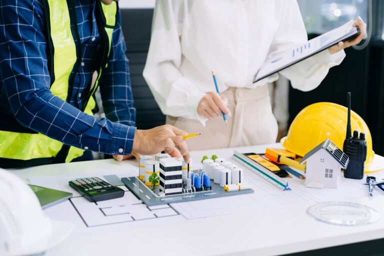 Creative architect projecting on the big drawings with architectural project at construction site at desk in modern office